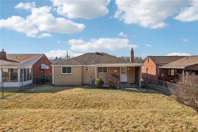 rear view of house featuring a yard, fence, brick siding, and central AC