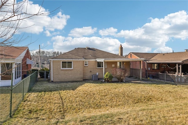 back of property with brick siding, a lawn, and fence