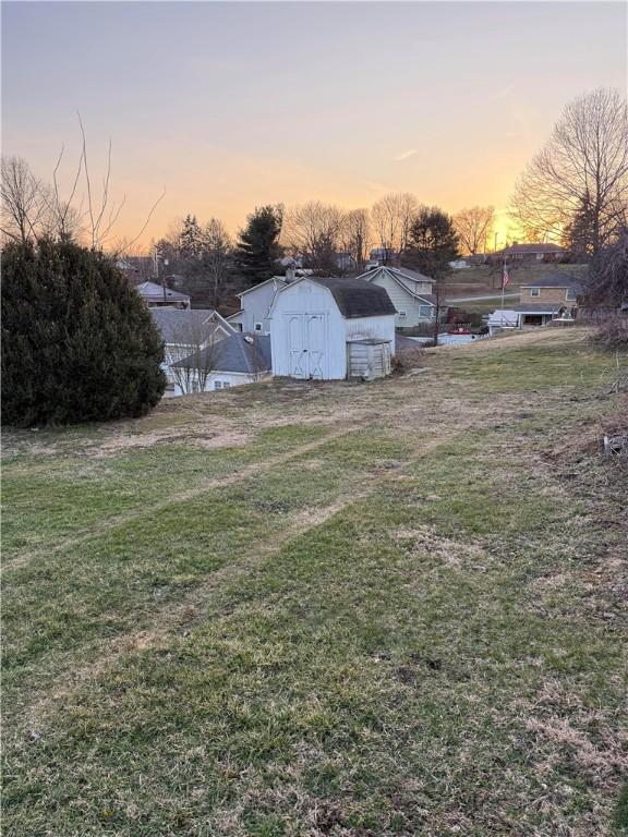 yard at dusk featuring a storage shed and an outdoor structure