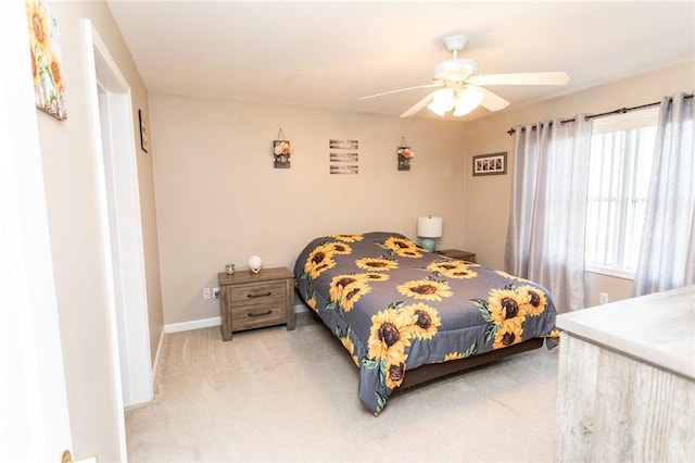 bedroom featuring baseboards, light colored carpet, and a ceiling fan