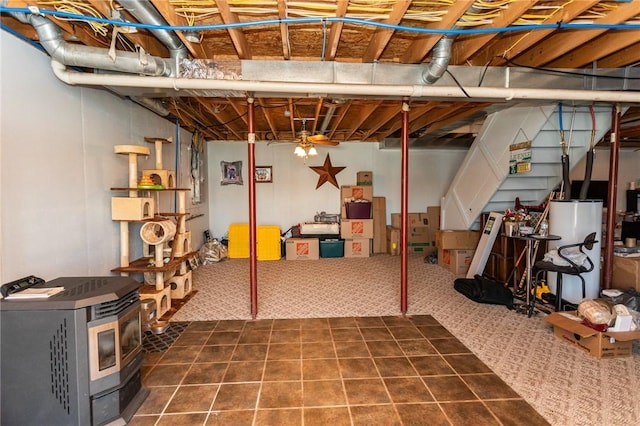 unfinished below grade area featuring a wood stove, dark colored carpet, and water heater