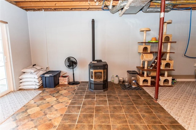 basement featuring a wood stove and tile patterned flooring