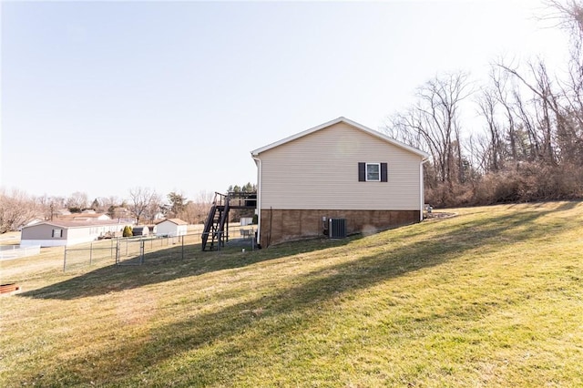 view of property exterior with stairway, a lawn, central AC, and fence