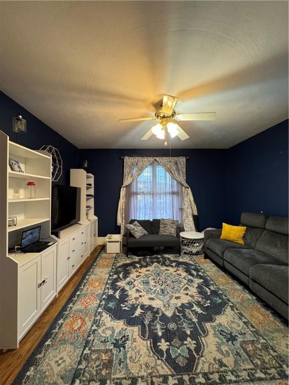 living area with dark wood-type flooring and ceiling fan