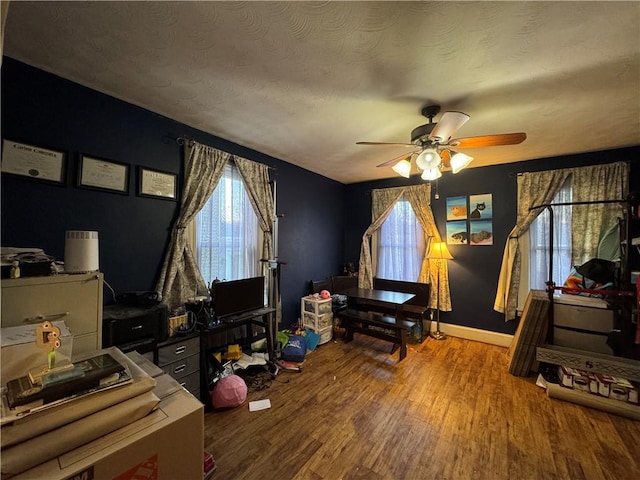 bedroom with ceiling fan, baseboards, a textured ceiling, and wood finished floors