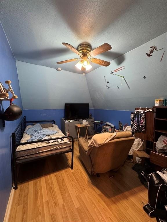 living room with a textured ceiling, light wood-style floors, a ceiling fan, and vaulted ceiling