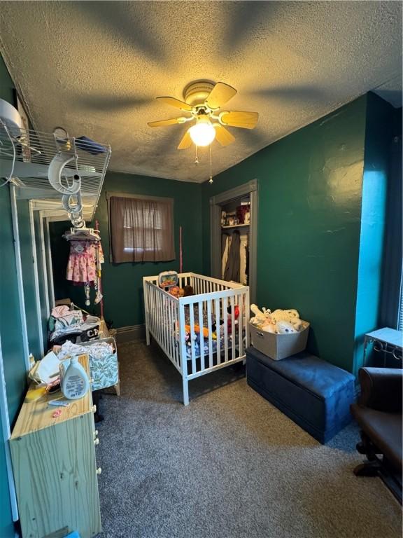 carpeted bedroom featuring a textured ceiling and a ceiling fan