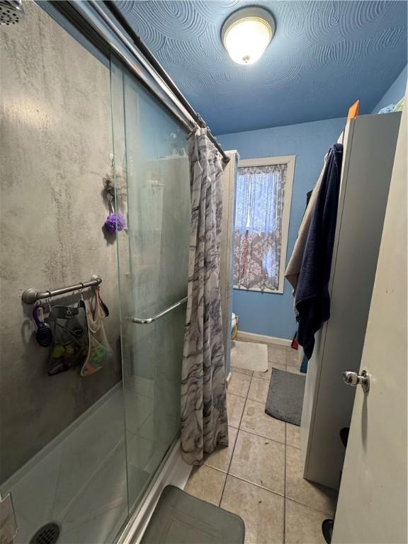 bathroom featuring tile patterned floors, a textured ceiling, and a shower stall