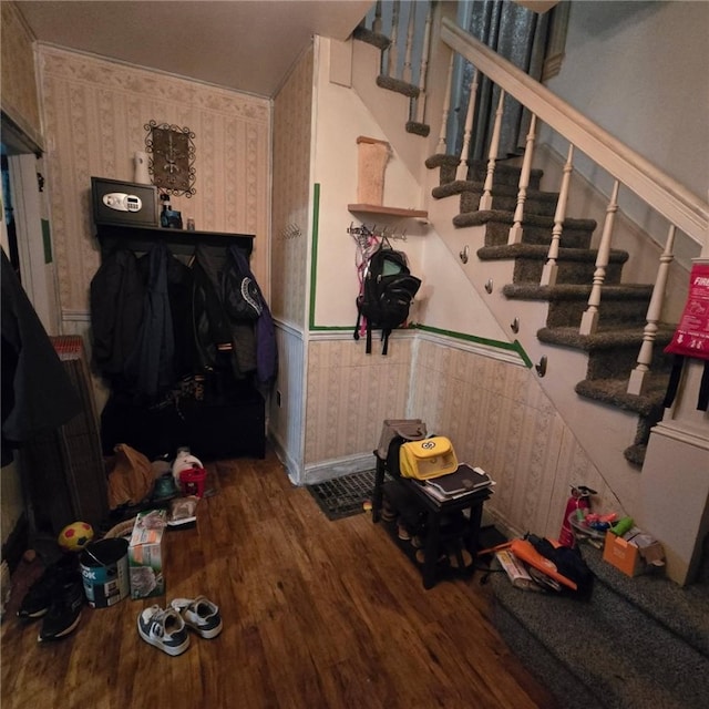 stairway with baseboards, wood finished floors, and wallpapered walls