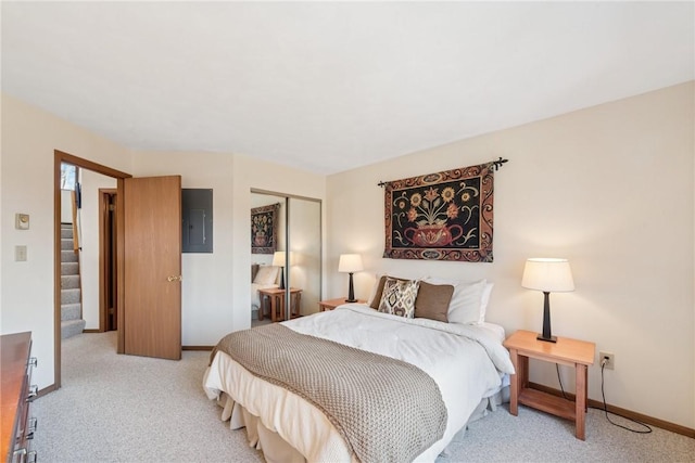 bedroom with a closet, baseboards, light carpet, and electric panel