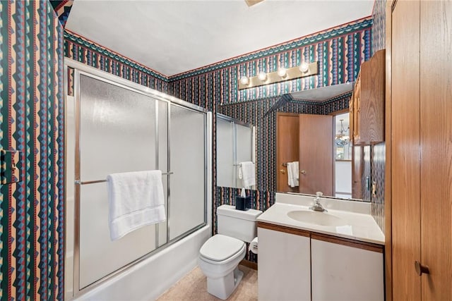 full bathroom with combined bath / shower with glass door, toilet, vanity, and wallpapered walls