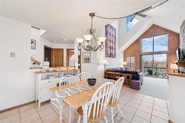 dining area featuring wooden walls, baseboards, an inviting chandelier, light tile patterned flooring, and high vaulted ceiling