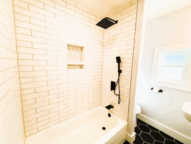 full bathroom featuring tile patterned floors, toilet, baseboards, and shower / bathtub combination