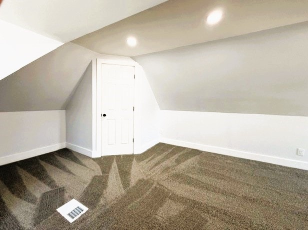 additional living space featuring visible vents, baseboards, vaulted ceiling, carpet floors, and recessed lighting