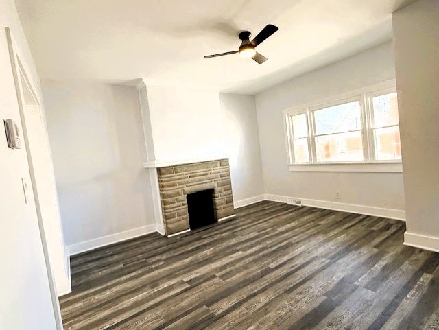 unfurnished living room featuring dark wood-style floors, baseboards, ceiling fan, and a fireplace