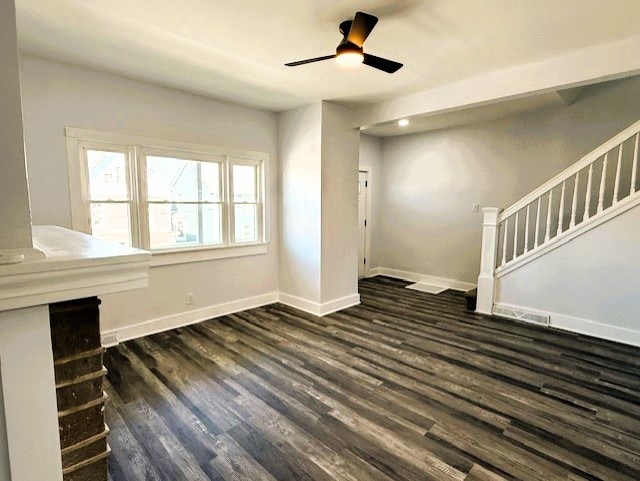 unfurnished living room with stairs, a ceiling fan, baseboards, and dark wood-style flooring