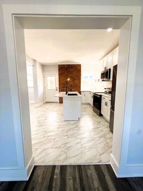 kitchen featuring electric range, a sink, stainless steel microwave, freestanding refrigerator, and white cabinets