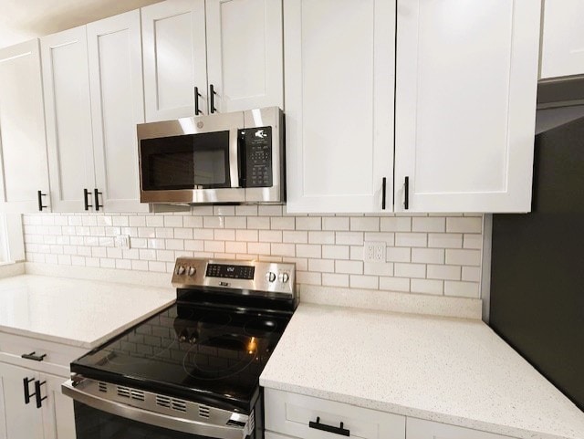 kitchen featuring white cabinets, light stone counters, tasteful backsplash, and stainless steel appliances