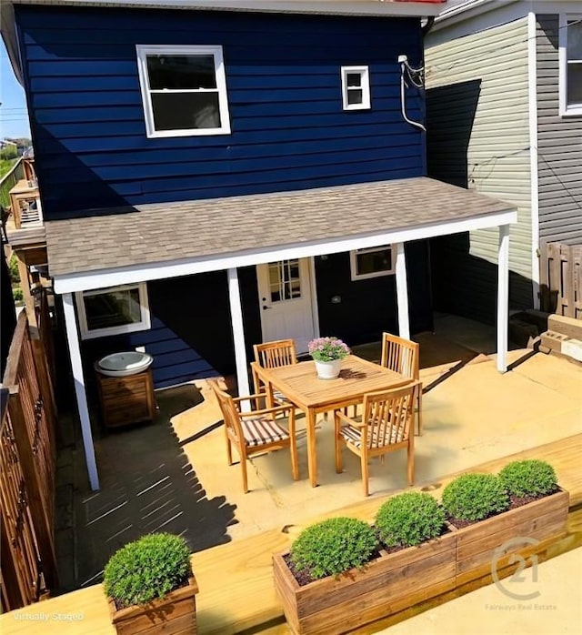 rear view of house with roof with shingles, outdoor dining space, and a patio area