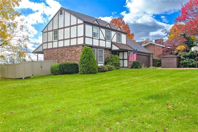 exterior space featuring a shed, an attached garage, a front lawn, and fence