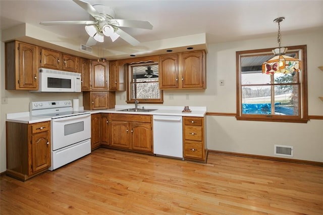 kitchen featuring a sink, visible vents, white appliances, and brown cabinets