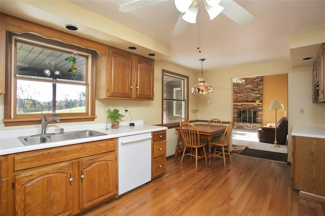 kitchen with a sink, dishwasher, brown cabinetry, and light wood finished floors