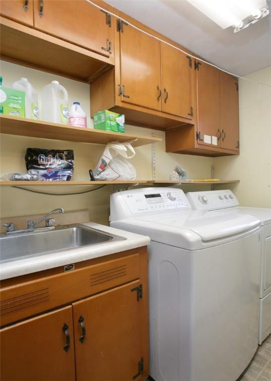 clothes washing area featuring a sink, cabinet space, and washing machine and clothes dryer