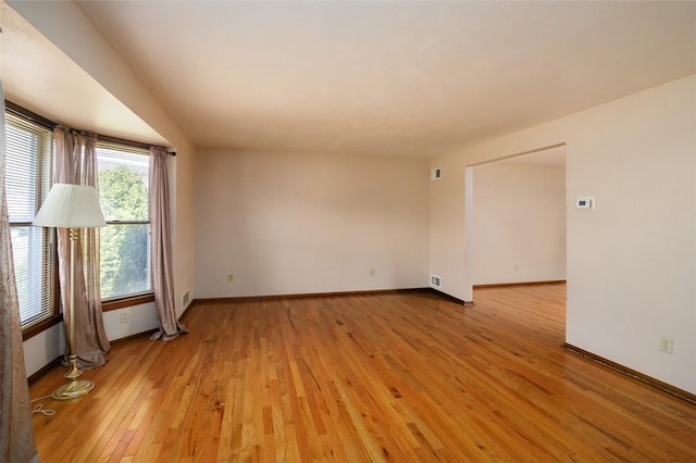 spare room with baseboards and light wood finished floors