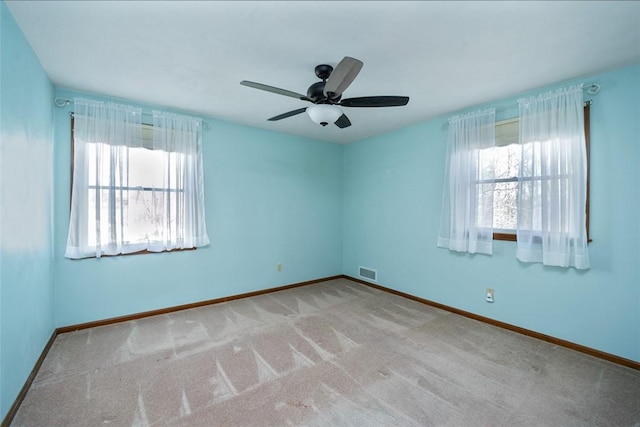 carpeted empty room with visible vents, a ceiling fan, and baseboards