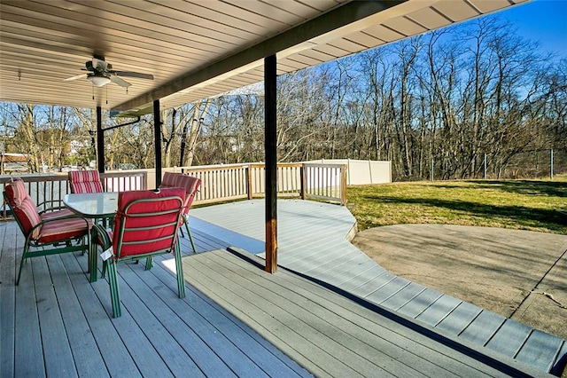 wooden terrace with outdoor dining space, a yard, and ceiling fan