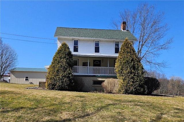 exterior space featuring a porch, a lawn, roof with shingles, and a chimney