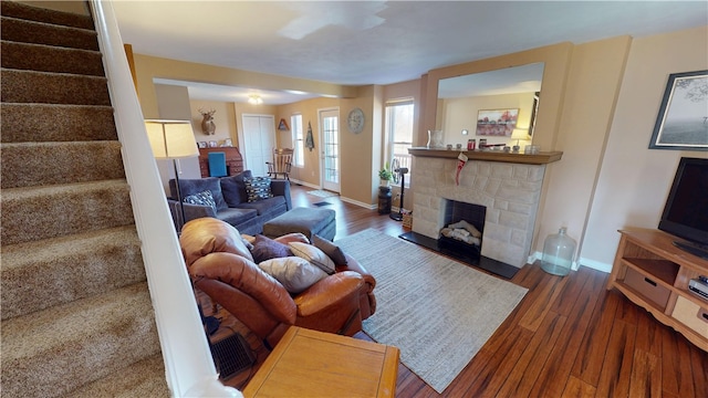 living area featuring stairway, baseboards, wood finished floors, and a fireplace