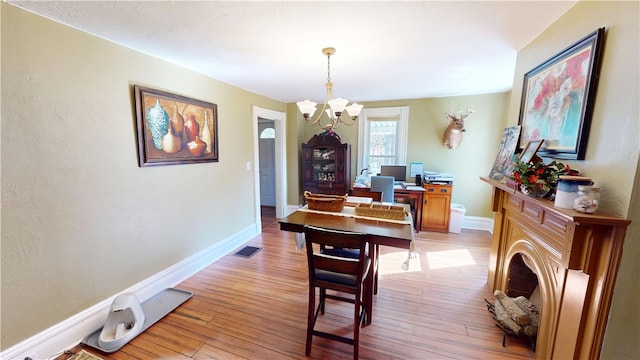 dining space featuring visible vents, light wood-style flooring, baseboards, and an inviting chandelier