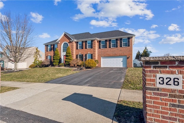 view of front of home featuring aphalt driveway, an attached garage, brick siding, and a front lawn