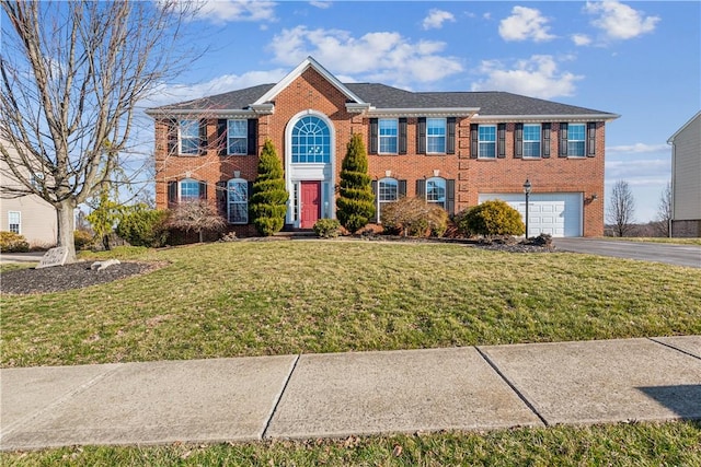 colonial inspired home featuring aphalt driveway, a garage, a front lawn, and brick siding