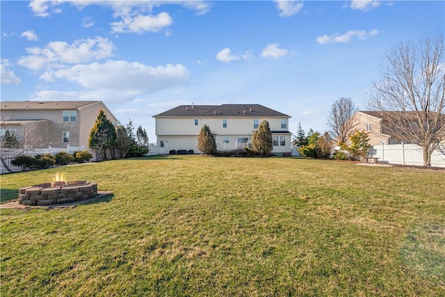 back of house featuring a fire pit, a lawn, and fence