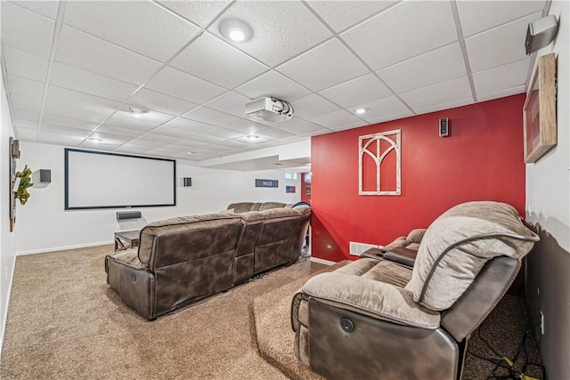 cinema room with a paneled ceiling, visible vents, baseboards, and carpet