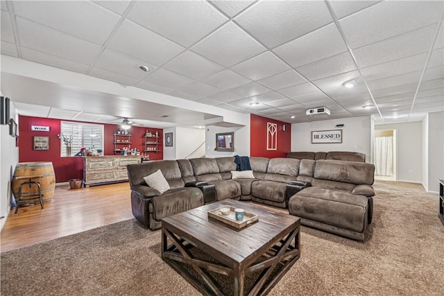 living area with a drop ceiling, wood finished floors, carpet floors, baseboards, and indoor bar