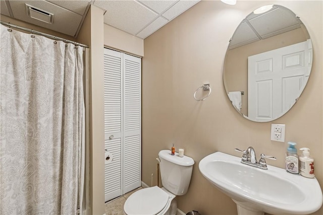 bathroom with visible vents, toilet, a closet, a paneled ceiling, and a sink