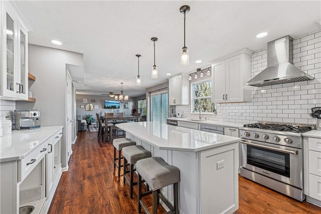 kitchen with dark wood finished floors, stainless steel range, wall chimney range hood, and white cabinetry