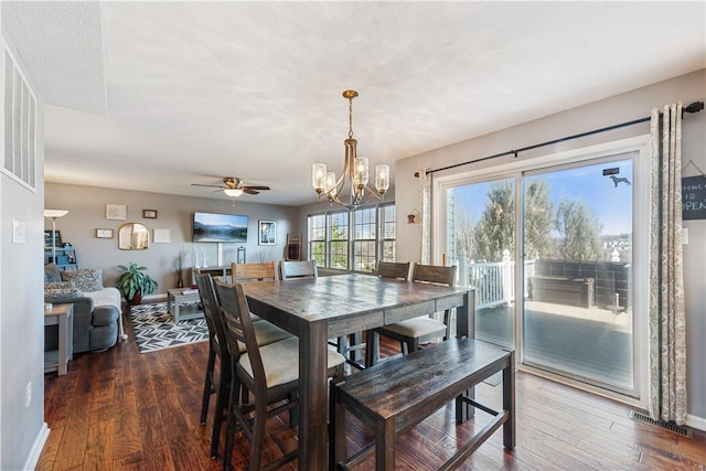 dining area with ceiling fan with notable chandelier, dark wood-style floors, visible vents, and baseboards