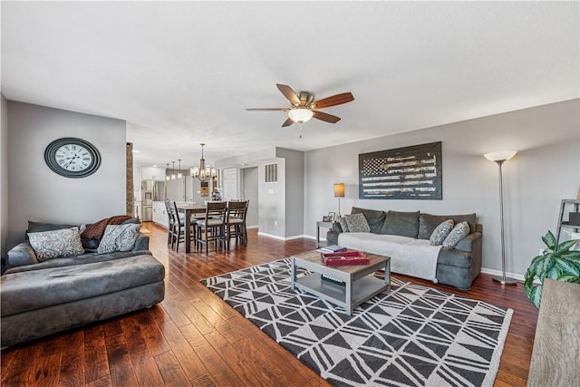 living area with baseboards, hardwood / wood-style floors, and ceiling fan with notable chandelier