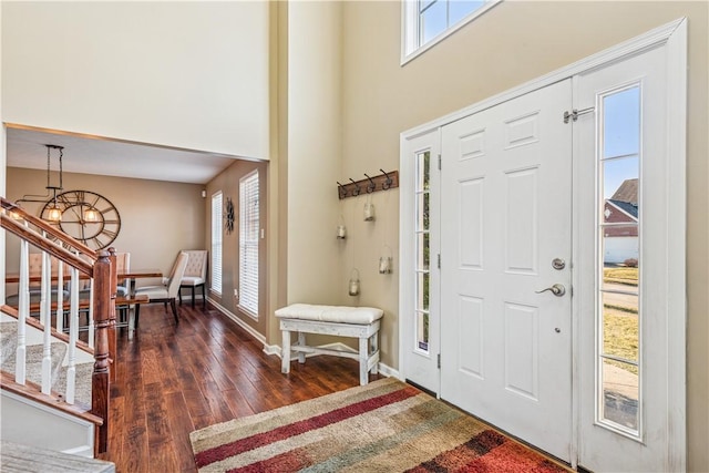 entryway with baseboards, a chandelier, stairs, hardwood / wood-style floors, and a towering ceiling