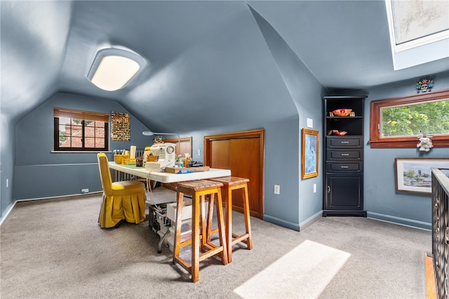 carpeted dining room with lofted ceiling with skylight and baseboards