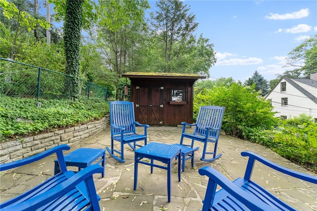 view of patio / terrace with a storage unit, an outdoor structure, and fence