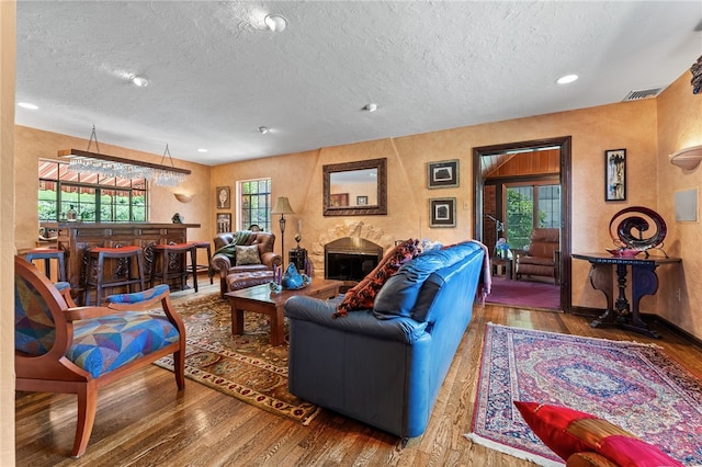 living room featuring visible vents, a fireplace, bar area, wood-type flooring, and a textured wall