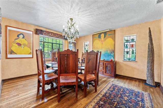 dining space featuring visible vents, baseboards, wood finished floors, a notable chandelier, and a textured ceiling