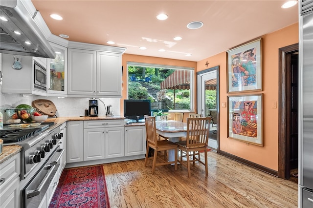 kitchen with light wood finished floors, white cabinets, glass insert cabinets, and exhaust hood