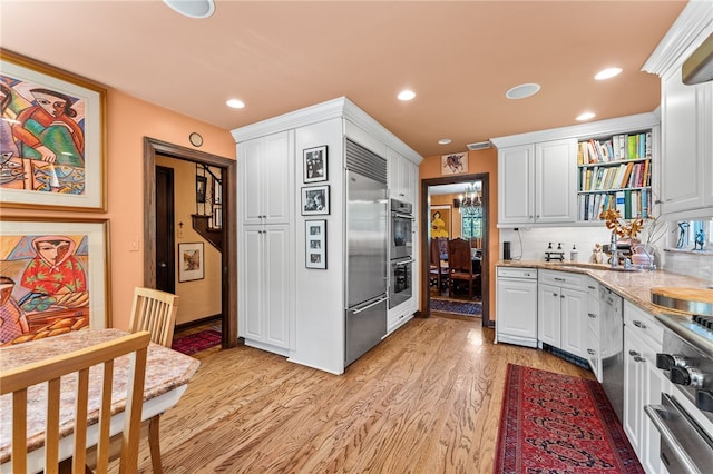 kitchen with recessed lighting, stainless steel appliances, light wood finished floors, and white cabinetry