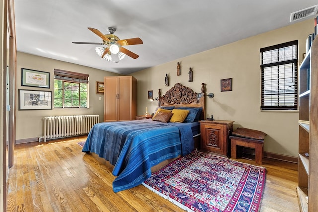 bedroom with radiator heating unit, baseboards, visible vents, and light wood finished floors